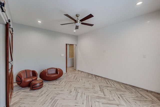 unfurnished room featuring a barn door, ceiling fan, and light parquet flooring