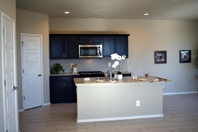 kitchen with wood tiled floor, stainless steel microwave, backsplash, and baseboards