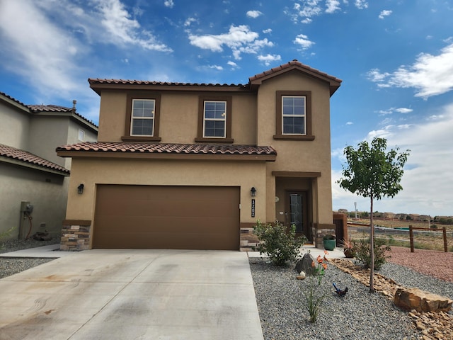 mediterranean / spanish home with an attached garage, fence, driveway, stone siding, and stucco siding