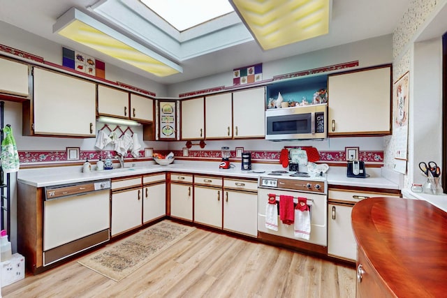 kitchen featuring light wood-type flooring, white cabinets, white appliances, and sink