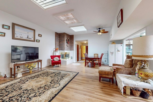 living room featuring light wood-type flooring, a skylight, and ceiling fan