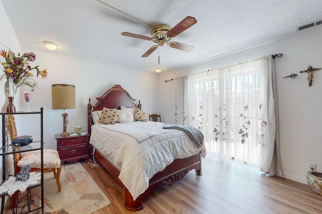 bedroom featuring ceiling fan, a textured ceiling, and light hardwood / wood-style flooring