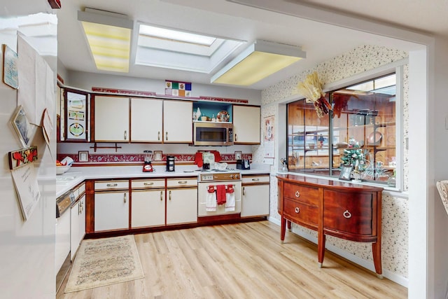 kitchen featuring light hardwood / wood-style flooring, white appliances, white cabinetry, and a skylight