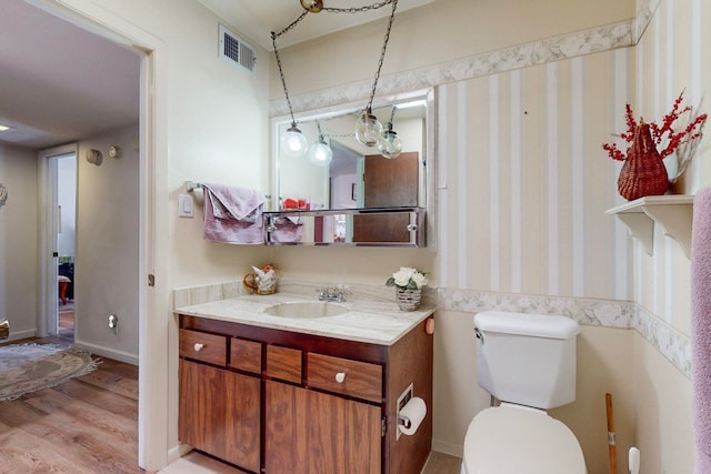 bathroom with vanity, toilet, and hardwood / wood-style floors