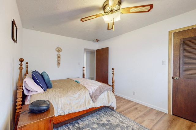 bedroom with a textured ceiling, wood-type flooring, and ceiling fan