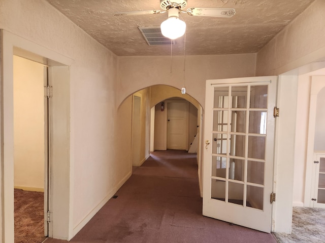 corridor featuring a textured ceiling and carpet flooring