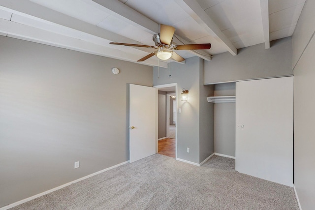 unfurnished bedroom featuring beamed ceiling, ceiling fan, light carpet, and a closet