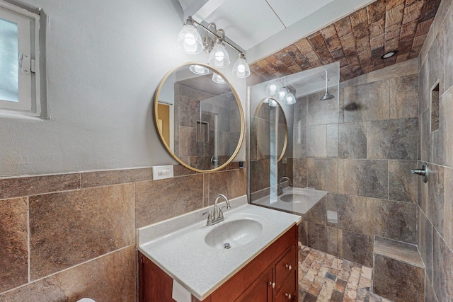 bathroom featuring a tile shower, vanity, and tile walls