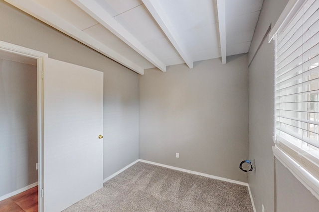 spare room featuring light colored carpet and beam ceiling