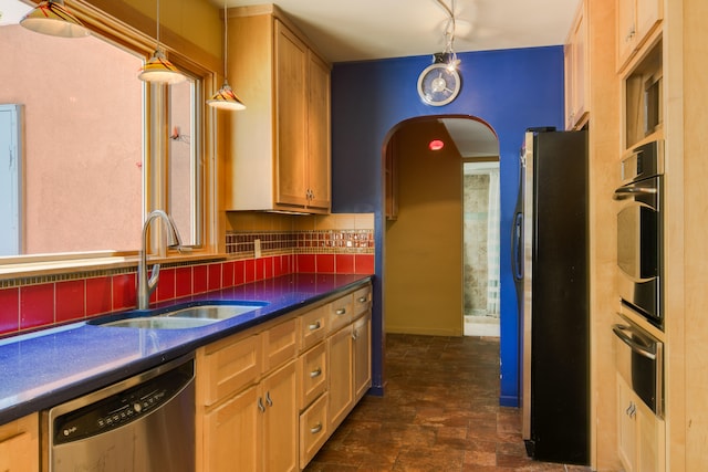 kitchen featuring decorative backsplash, stainless steel appliances, sink, and hanging light fixtures