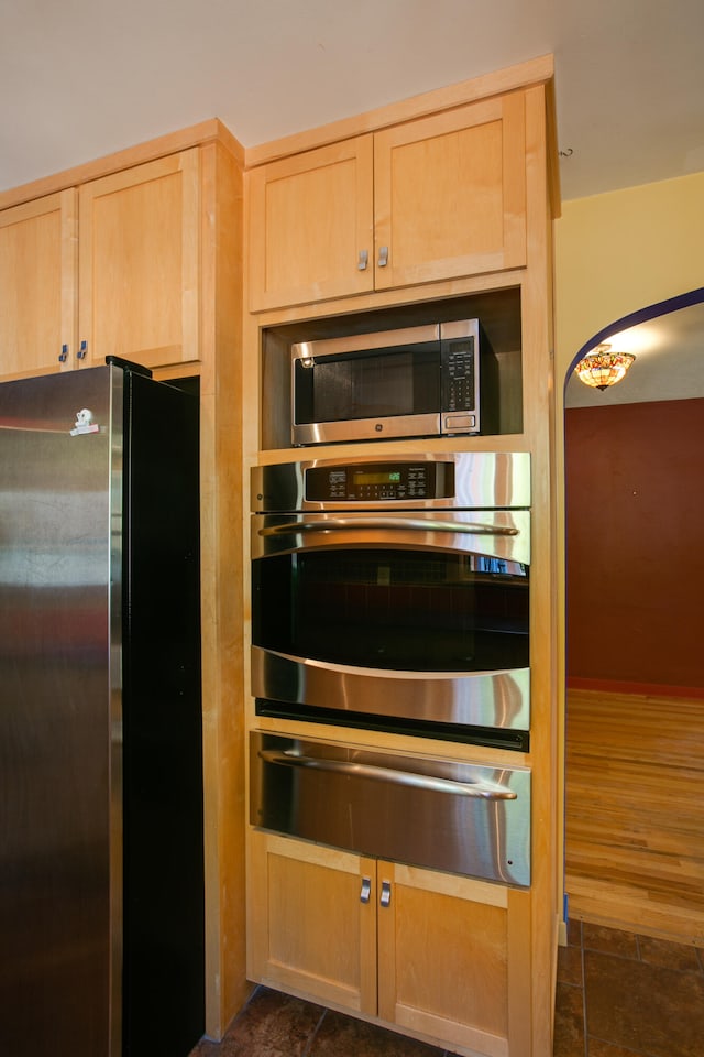 kitchen with appliances with stainless steel finishes, light brown cabinets, and dark hardwood / wood-style flooring