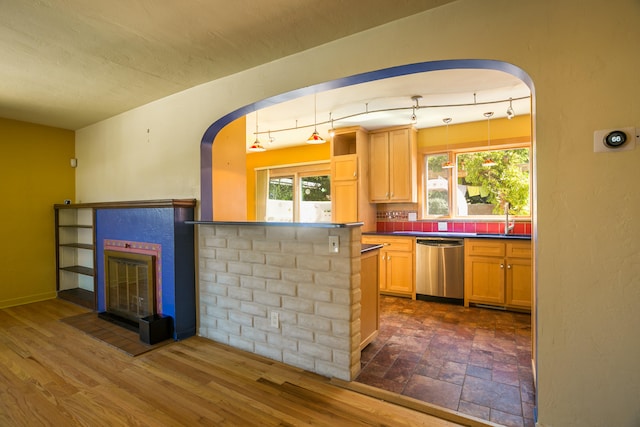 kitchen with dark wood-type flooring, light brown cabinets, stainless steel dishwasher, and sink