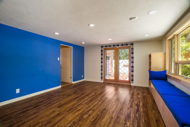 interior space with a textured ceiling, dark hardwood / wood-style floors, and french doors