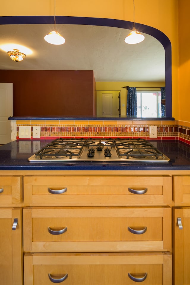 kitchen featuring pendant lighting, white gas cooktop, and backsplash