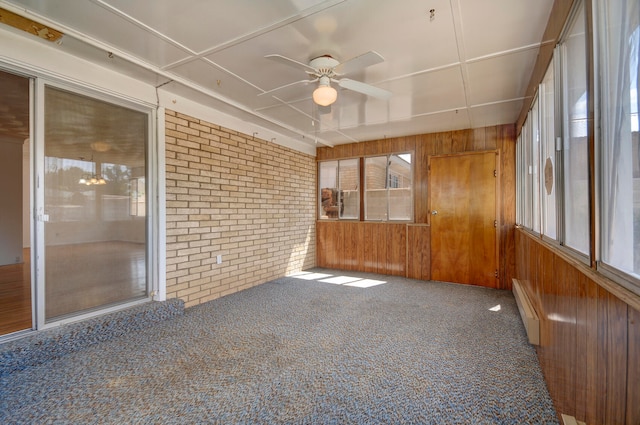 unfurnished sunroom featuring a baseboard heating unit and ceiling fan