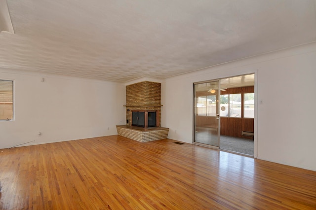 unfurnished living room featuring light wood-type flooring, a fireplace, and baseboard heating