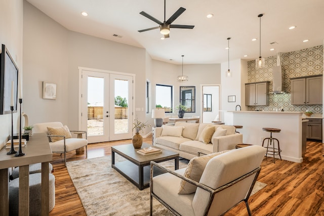 living room with a towering ceiling, ceiling fan, dark hardwood / wood-style floors, and french doors