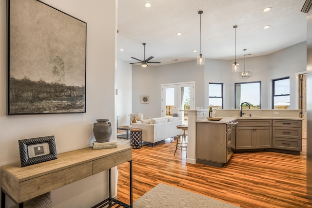 kitchen featuring gray cabinetry, decorative light fixtures, light hardwood / wood-style floors, ceiling fan, and a kitchen breakfast bar