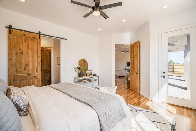 bedroom with light hardwood / wood-style flooring, access to exterior, ceiling fan, and a barn door