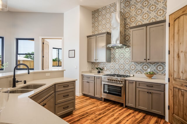 kitchen with double oven range, sink, dark hardwood / wood-style floors, vaulted ceiling, and wall chimney range hood