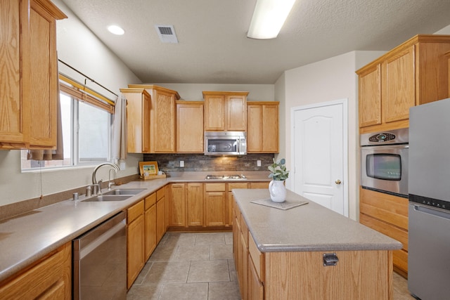 kitchen with backsplash, light tile patterned floors, stainless steel appliances, sink, and a center island