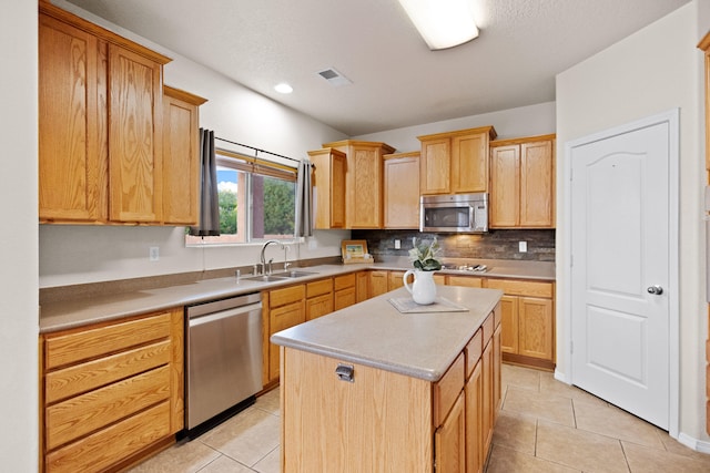 kitchen with a kitchen island, stainless steel appliances, backsplash, sink, and light tile patterned floors