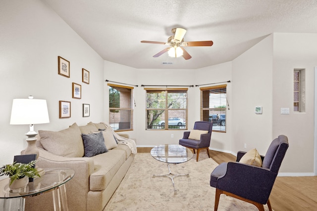 living room with light hardwood / wood-style flooring, a textured ceiling, and ceiling fan