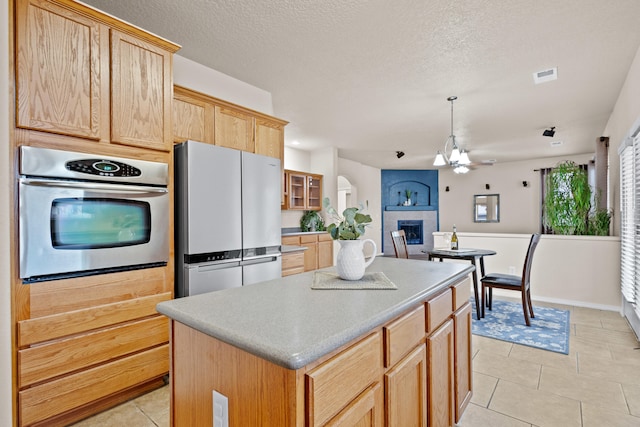 kitchen with a center island, a textured ceiling, stainless steel appliances, and a tile fireplace