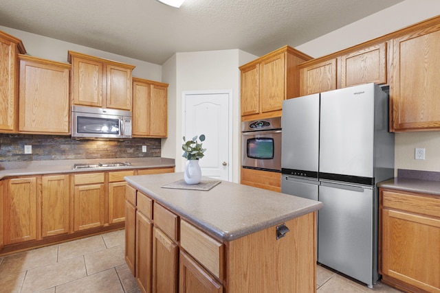 kitchen with appliances with stainless steel finishes, decorative backsplash, a center island, and light tile patterned floors