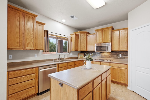 kitchen featuring appliances with stainless steel finishes, a center island, sink, and light tile patterned floors