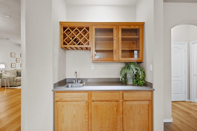 bar with sink, light hardwood / wood-style flooring, and a textured ceiling