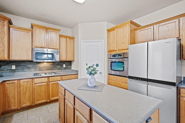 kitchen with light tile patterned flooring, stainless steel appliances, and backsplash