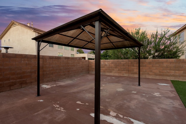 patio terrace at dusk with a gazebo, a yard, and ceiling fan