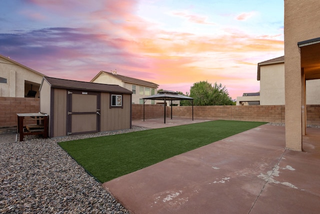 yard at dusk featuring a patio and a shed