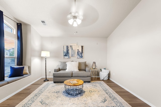 living area featuring ceiling fan, wood-type flooring, and lofted ceiling