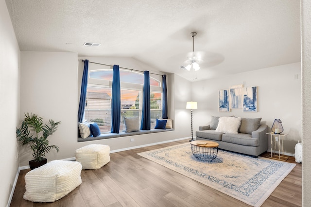 living room featuring hardwood / wood-style floors, ceiling fan, a textured ceiling, and vaulted ceiling