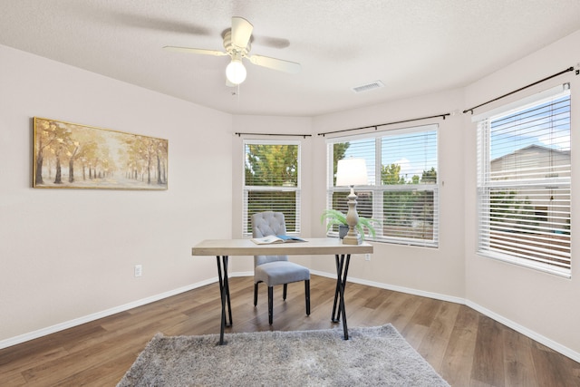 office space with ceiling fan, a textured ceiling, wood-type flooring, and a wealth of natural light