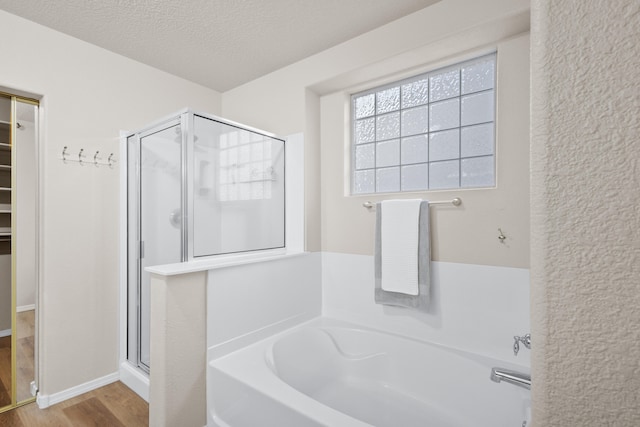 bathroom featuring a textured ceiling, shower with separate bathtub, and hardwood / wood-style floors