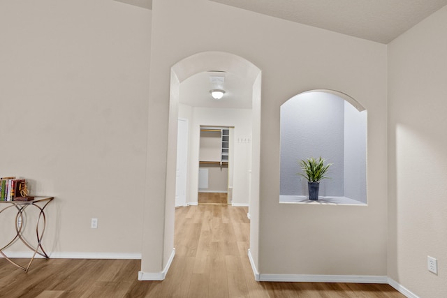 hall with lofted ceiling and light wood-type flooring