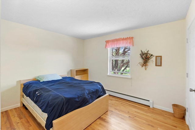 bedroom with baseboard heating and hardwood / wood-style flooring