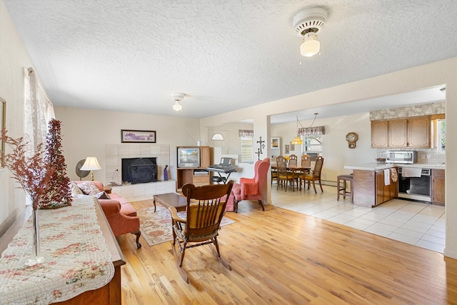 living room with a textured ceiling, light hardwood / wood-style floors, and a tiled fireplace