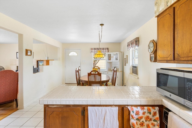 kitchen with cooling unit, tile countertops, hanging light fixtures, and light tile patterned flooring