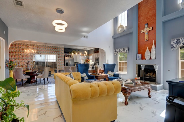 living room featuring a notable chandelier, a high ceiling, and a textured ceiling