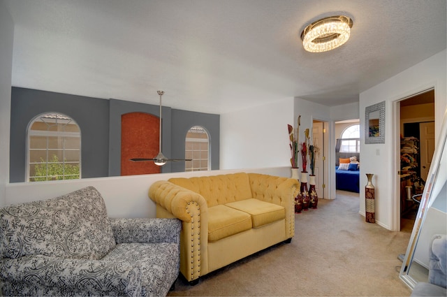 living room with ceiling fan, light colored carpet, and a textured ceiling