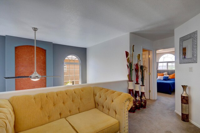 living room with a textured ceiling, carpet flooring, and ceiling fan