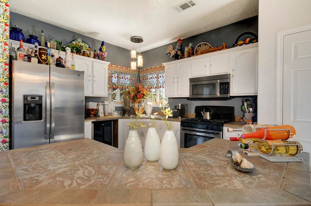 kitchen with stainless steel appliances, white cabinets, beverage cooler, and hanging light fixtures