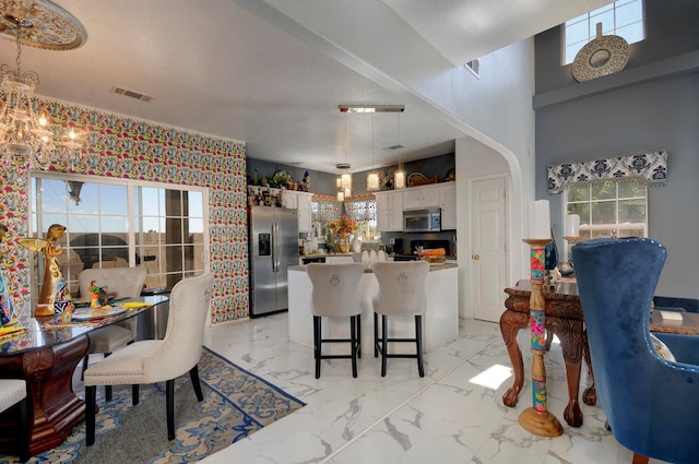 kitchen featuring appliances with stainless steel finishes, white cabinetry, a kitchen breakfast bar, and a wealth of natural light