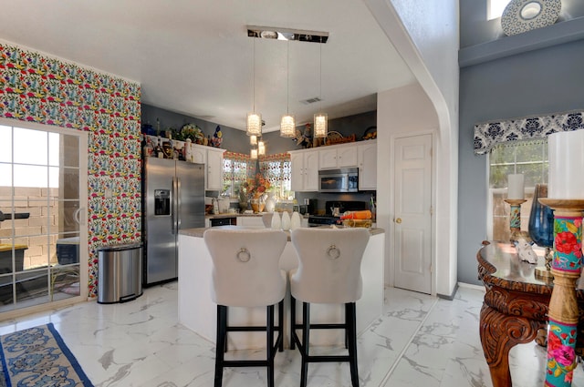 kitchen featuring white cabinets, stainless steel appliances, hanging light fixtures, and a wealth of natural light