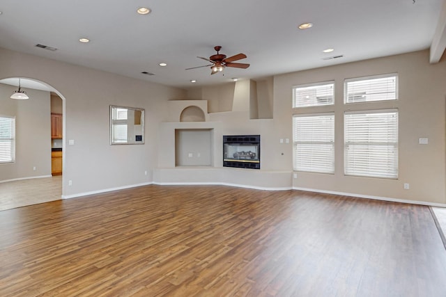 unfurnished living room featuring hardwood / wood-style flooring, ceiling fan, and plenty of natural light