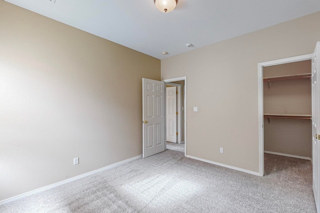 unfurnished bedroom featuring light colored carpet, a closet, and a walk in closet